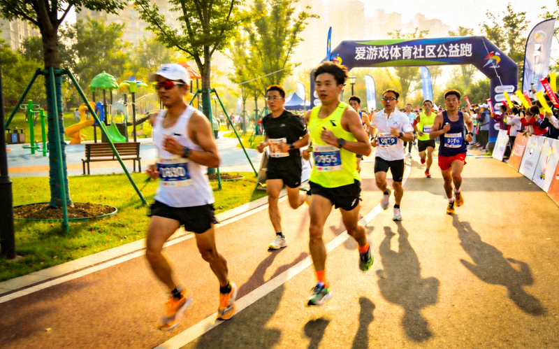 爱游戏体育社区公益跑活动现场：跑者在城市公园赛道上奔跑的画面